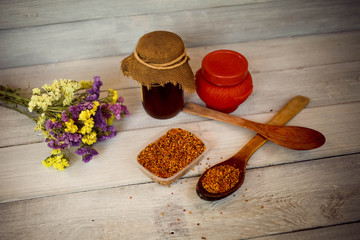 Honey , bee pollen and flowers on a white wooden background