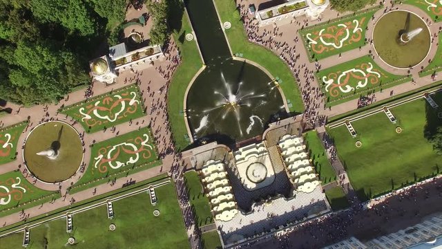 Top aerial view of beautiful Peterhof palace and grand cascade. Sparkling fountains. Golden statues. Unique aerial drone flight. Warm sunny day.