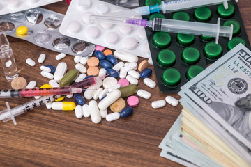 dollars with syringe and pills