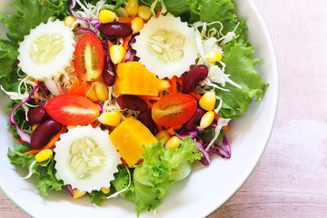 Top view of a bowl of mixed salad on a wooden table.