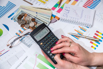 women hold calculator above business chart with money