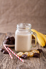 Banana smoothie  with chocolate in glass jar with drinking straw