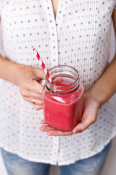 Young woman is holding detox drink, smoothie in glass jar.
