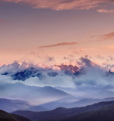 Obraz na płótnie Canvas High mountain range in the clouds during sunrise. Beautiful panoramic landscape