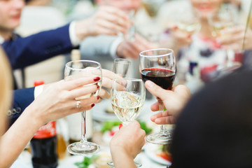 People hold in hands glasses with white and  red wine