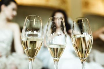 Glasses with champagne stand on the table in the front of bride.