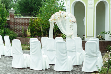 Chairs covered with white cloth stand in the front of wedding al