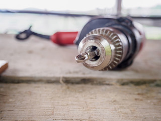 Close up electric drill at work site on wooden board