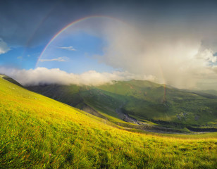 Rainbow in mountain valley during sunset. Beautiful natural landscape