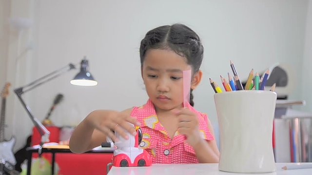 Asian little girl using the color pencil sharpener