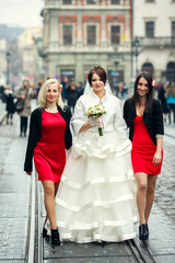 Bride walks with pretty bridesmaids along the tramways