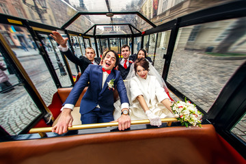 Obraz na płótnie Canvas Newlyweds sit in a tourist tram together with friends