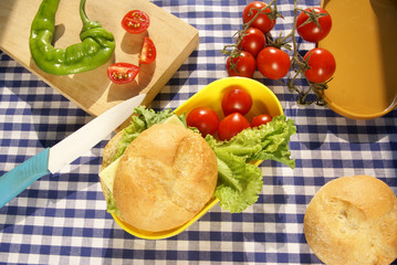 Cooking lunchbox. Yellow box lunch sandwich with cheese and a knife lying on a cutting board, fresh vegetables (pepper, tomatoes, lettuce)