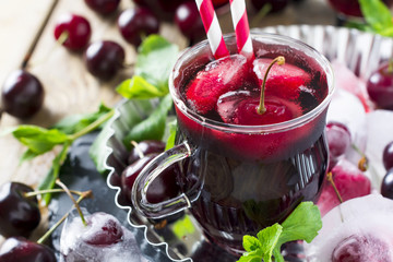 Fresh cherry juice in a glass with ice on a wooden background. Rustic style. Selective focus.