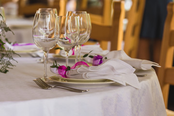 Wedding summer table decoration with flowers. White plates, forks, knifes and wineglasses