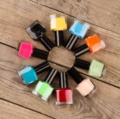 Coloured nail polish bottles stacked circle on brown wooden table