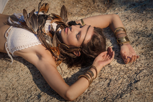 attractive young boho woman lying on stone