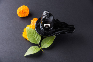 Shiva Linga made up of black stone decorated with flowers & bael leaf known as Aegle marmelos, over...