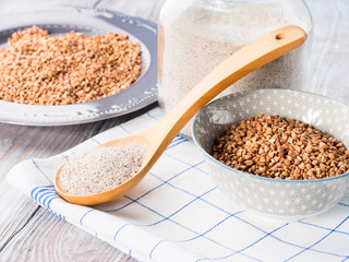 Buckwheat grain and flour on rustic wooden table