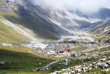 Fototapeta premium Mountain huts in valley under fog