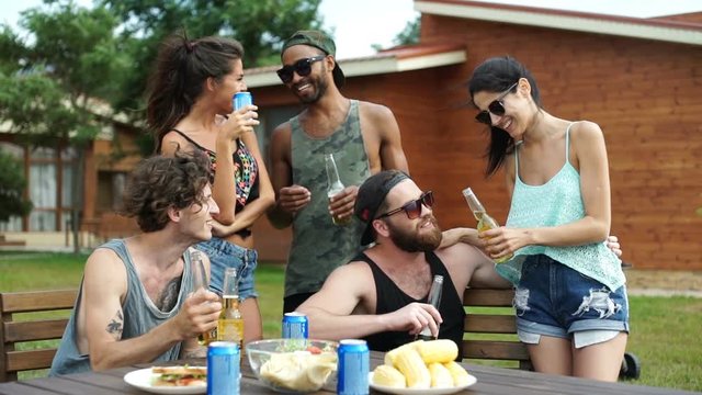 Group of young beautiful happy teenagers talking and drinking beer at the picnic area
