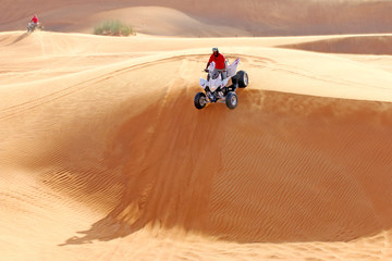 Extreme sport. ATV drives off the sand dunes