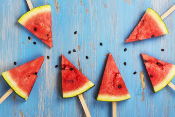 Watermelon popsicles over blue wooden background