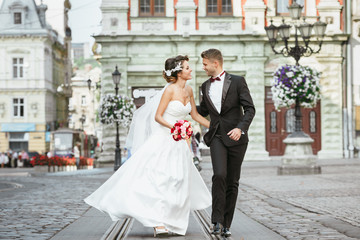 Married couple walking in the city and holding bouquet