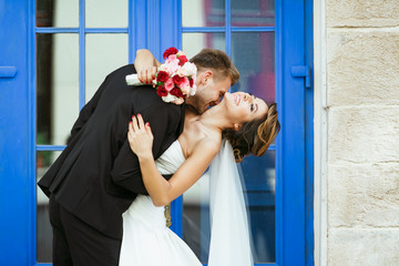 Bride and groom embracing near blue door