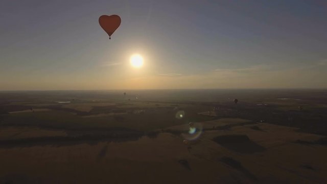 Red balloon in the shape of a wheat heart.Balloon on the background of the sun.Aerial view:Hot air balloon in the sky over a field in the countryside in the beautiful sky and sunset.Aerostat fly in