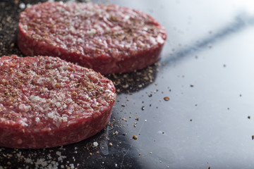 Meat for burgers, grilling, barbecue, bbq. Fresh, spicy, uncooked, delicious beef for hamburgers on dark background with copy space closeup
