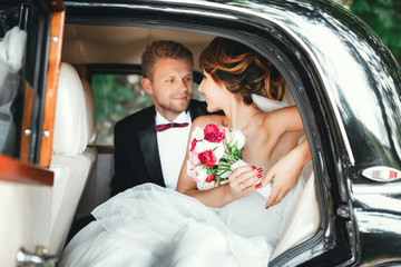 Bride and groom sitting in wedding car