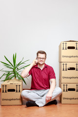 Junger Mann telefoniert mit Smartphone im neuen Eigenheim