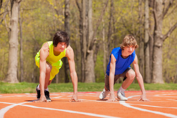 Fototapeta premium Two teenage boys ready to start running on a track