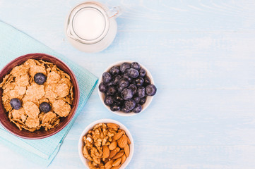 healthy breakfast, cornflakes blueberry and milk, nuts, almond with text space top view close-up instagram filter