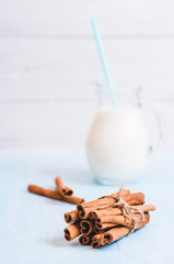 Pitcher glass of milk with cinnamon and cocktail tube on blue wooden background instagram filter