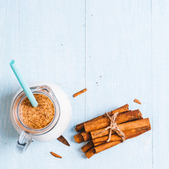 Pitcher glass of milk with cinnamon on a blue wooden background, instagram filter space for text