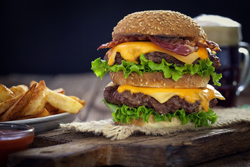 Cheeseburger with potato and beer on wooden table  