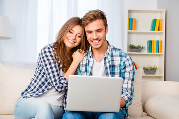 Portrait of happy young family sitting on sofa with laptop