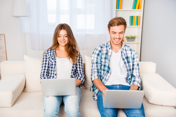 Happy young man and woman working on two laptops