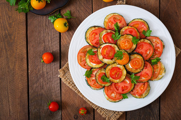Dish with a snack of fried zucchini with tomatoes. Top view