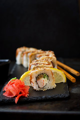 Traditional Japanese food - sushi, rolls and sauce on a black background.