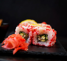 Traditional Japanese food - sushi, rolls and sauce on a black background.