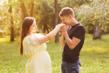 the young beautiful pregnant woman with the husband in park in summer day

