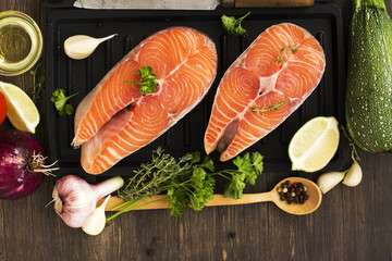 Raw salmon steaks over wooden background