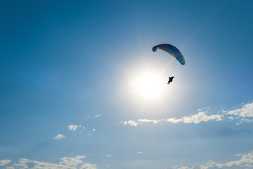 Paragliding in the sky. Man flying a paraglider on the sun.
