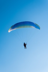 Paragliding in the sky. Man flying a paraglider on the sun.