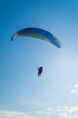 Paragliding in the sky. Man flying a paraglider on the sun.