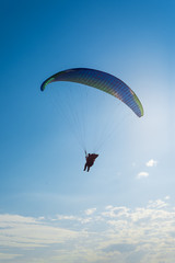 Paragliding in the sky. Man flying a paraglider on the sun.