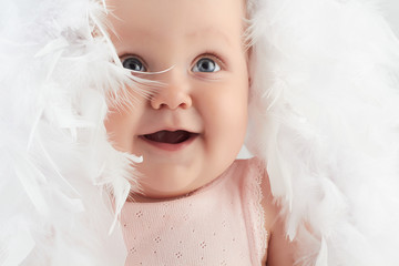 smiling baby girl in feathers. little funny child.newborn